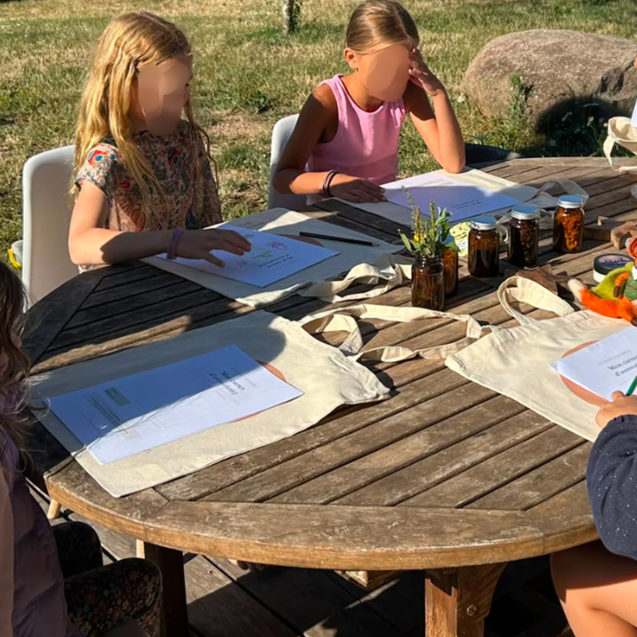 Table d'atelier enfant avec pots de baume maison, cire d'abeille et matériel de fabrication de cosmétiques naturels